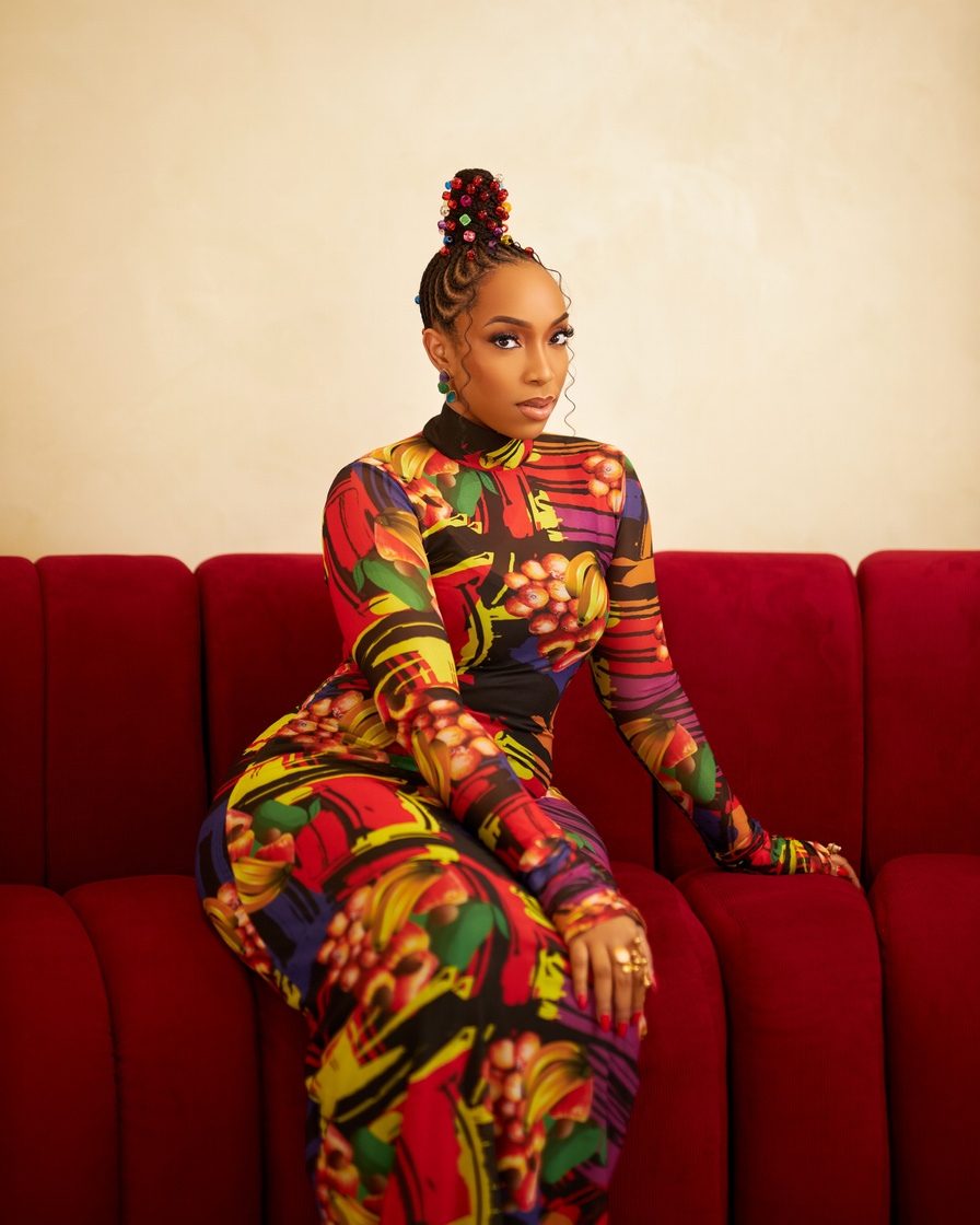 Eki Ogunbor in a printed catsuit on a red velvet sofa
